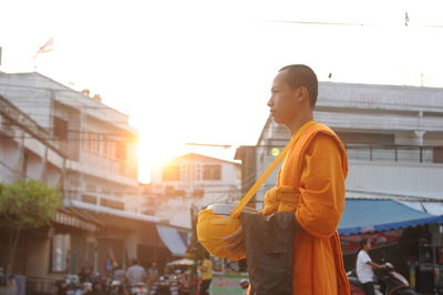 Full length of man standing on city against sky during sunset