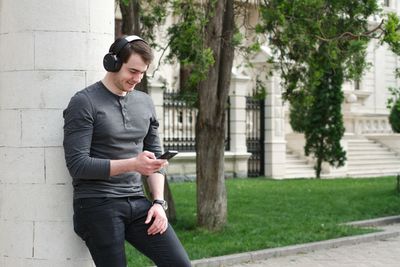 Full length of young man using mobile phone in city