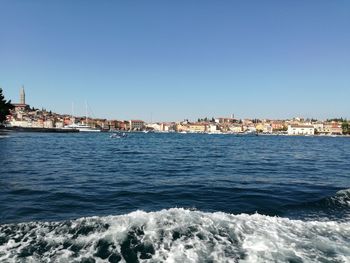 Sea in city against clear blue sky