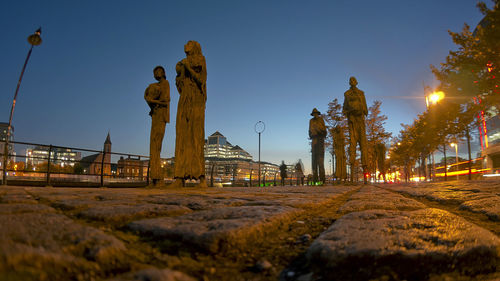 Statue in city against sky at night