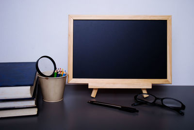 Close-up of blank blackboard with school supplies on table