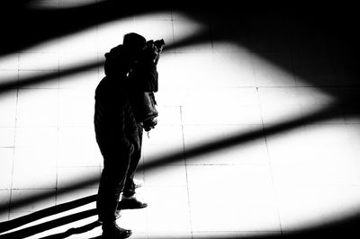 Silhouette man photographing against wall