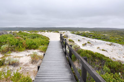 Boardwalk amidst sea against sky