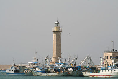 Sailboats moored at harbor against clear sky