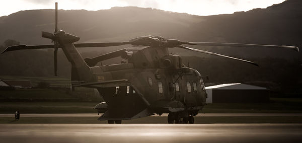 Military helicopter on airport runway against mountains