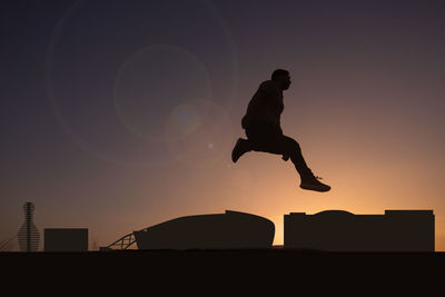 Silhouette man jumping against sky during sunset