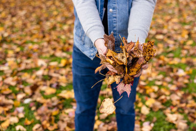 Midsection of woman holding autumn leaf