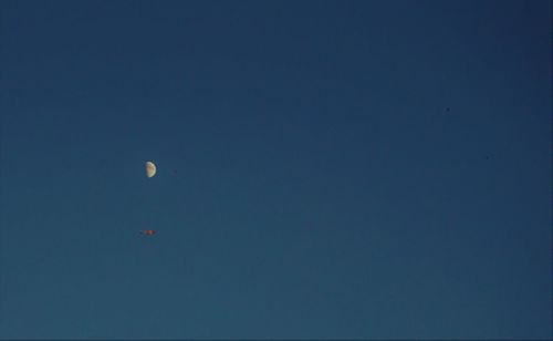 Low angle view of moon against clear blue sky