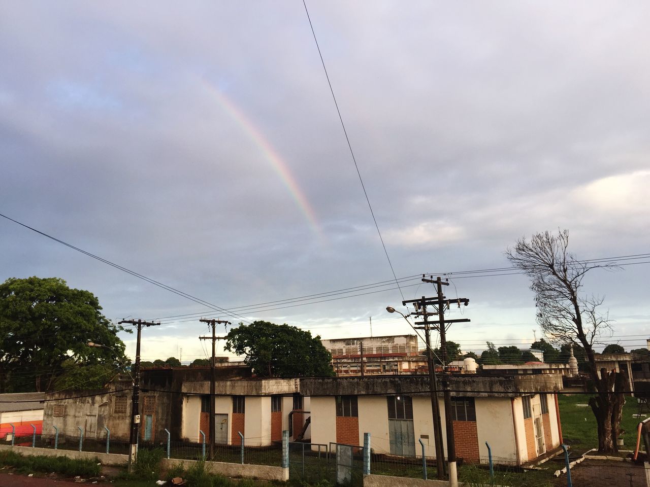 rainbow, cloud, sky, architecture, cable, electricity, built structure, nature, building exterior, tree, residential area, power line, electricity pylon, plant, technology, building, storm, suburb, house, city, day, no people, outdoors, power supply, residential district, transportation, street