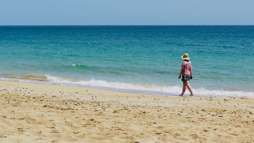 Full length of boy standing on beach against sky