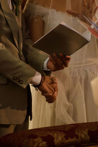 Midsection of couple holding hands at wedding ceremony