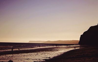 Scenic view of beach against clear sky during sunset