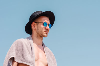 Man wearing sunglasses and hat against clear blue sky