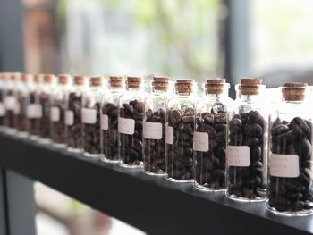 Close-up of roasted coffee beans in glass bottles on shelf