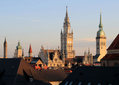 Church and houses in city against sky during sunset