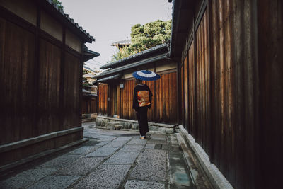 Woman standing on footpath amidst buildings