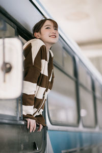 Portrait of young woman standing in bus