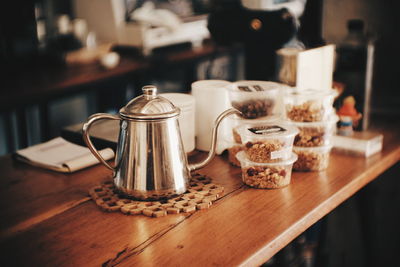 Close-up of kittle with containers on table