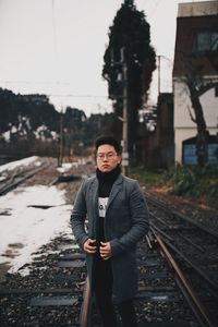 Portrait of man standing on railroad track during winter