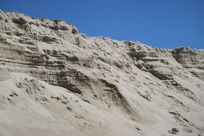 Low angle view of snowcapped mountains against clear blue sky