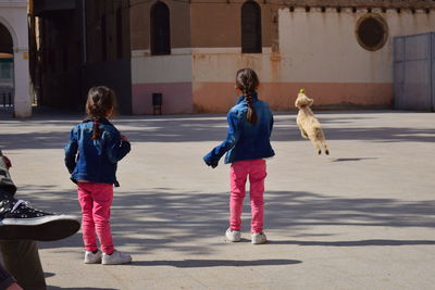 Rear view of siblings walking on road