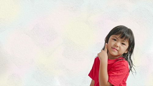 Portrait of cute girl standing against wall