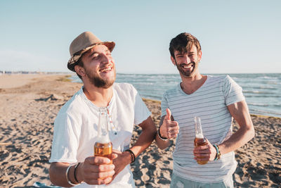 Friends enjoying at beach against sky