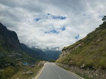 Road leading towards mountains against sky