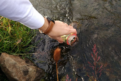 Close-up of hiker filling up jar with water from river