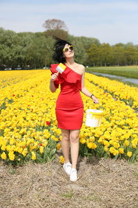 Full length of woman standing amidst yellow flowers