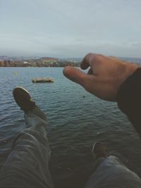 Low section of man holding sea against sky