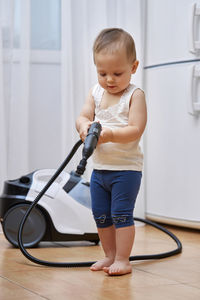 Portrait of cute boy playing with push scooter at home