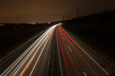 Light trails on road against sky at night