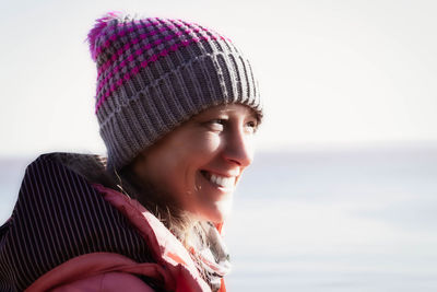 Smiling woman looking away while standing outdoors during winter