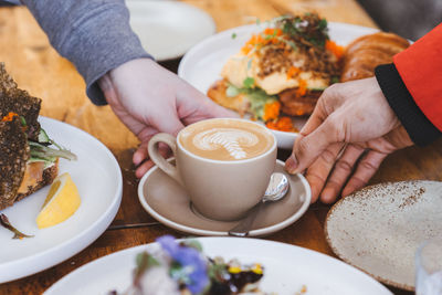 Midsection of man holding coffee cup on table