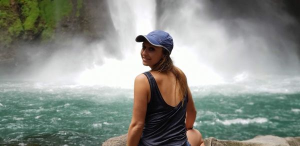 Portrait of woman sitting against waterfall