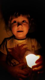 Portrait of cute girl with illuminated string lights at home