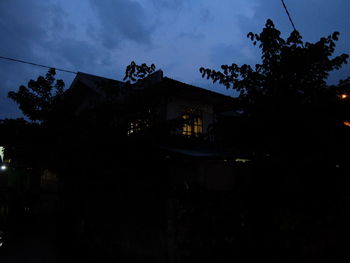 Low angle view of silhouette trees and buildings against sky