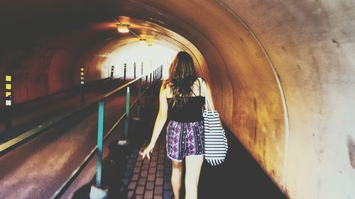 Rear view of woman walking in tunnel