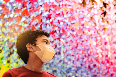 A boy wearing a face mask standing against a colorful textured background