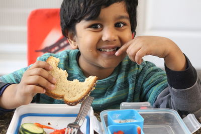 Portrait of smiling boy eating while sitting at table