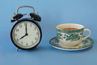 Close-up of clock on table against blue background