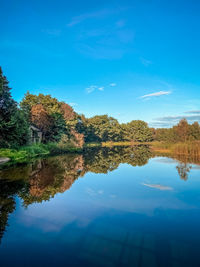 Reflection of trees in lake against blue sky