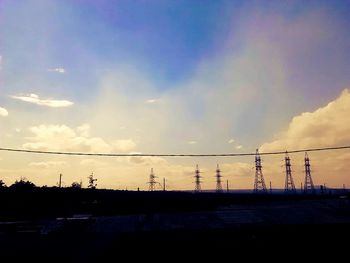 Electricity pylon against cloudy sky