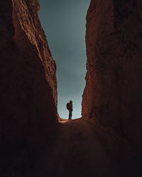 Mid distance of woman standing amidst rock formation during sunset
