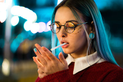 Close-up of young woman lighting cigarette