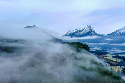 Scenic view of fog and mountains against sky