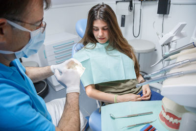 Midsection of dentist holding dental equipment by patient in clinic