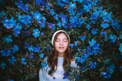 Portrait of young woman standing against plants