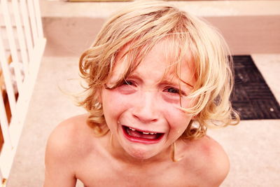 High angle portrait of shirtless boy crying at home